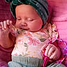 baby, infant, sleeping, headband, floral_clothing, pink_blanket, toy, green_pants, hand, face, cute, peaceful, child, newborn, soft_texture, indoor, portrait, closeup, resting, adorable