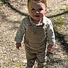 child, toddler, outdoor, forest, path, sunlight, shadow, overalls, sneakers, smiling, happy, nature, trees, young, person, standing, casual_clothing, daylight, curious, cute