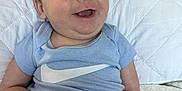 Evan is registered to the contest to win money with this photo: baby, smiling, infant, blue_onesie, white_pillow, quilted, cute, happy, child, person, sitting, indoors, soft_lighting, face, skin, mouth_open, expression, legs, arm, clothing