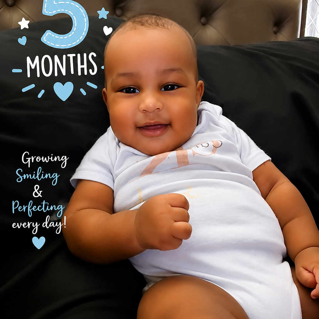 Camiri is registered to the contest to win money with this photo: baby, smiling, infant, white_onesie, black_background, headboard, cute, chubby_cheeks, lying_down, indoor, portrait, milestone, text_overlay, celebration, happy, child, young, skin, face, person