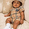 baby, blanket, bucket_hat, burberry, child, couch, cozy, cute, fashion, indoor, infant, person, pillow, plaid, portrait, relaxed, sneakers, socks, star_pattern, white_shoes