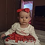 Eliana is registered to the contest to win money with this photo: baby, child, infant, girl, christmas, holiday, dress, bow, red, white, socks, bed, bedroom, furniture, door, television, indoor, portrait, cute, sitting