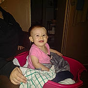 Eliana joined the competition — help win amazing prizes! baby, child, person, laundry_basket, blanket, pink, smile, indoor, adult, hand, clothing, face, seated, home, furniture, doorway, towel, flash, cozy, happy