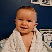 Nino participe au concours pour gagner de l'argent avec cette photo : baby, child, towel, smile, face, blue_wall, photograph, frame, indoor, person, skin, happy, portrait, young, cute, infant, wrapped, soft, background, home
