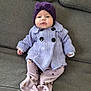 baby, child, infant, purple_hat, knitted_coat, couch, sofa, home_interior, soft_toys, comfortable, pastel_colors, sitting, cute, face, portrait, warm_clothing, indoor, relaxed, furniture, legs