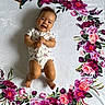 baby, smiling, infant, blanket, floral_pattern, flower, hummingbird, white_background, cute, lying_down, happy, child, portrait, soft_texture, colorful, nature_motif, clothing, one_person, indoors, playful