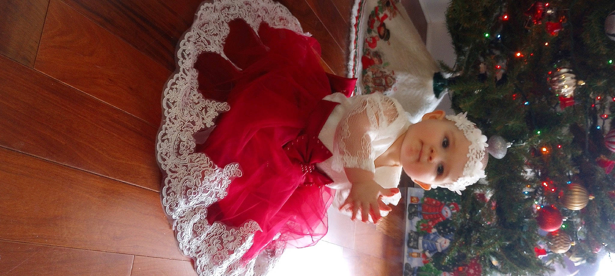 Elizabeth is registered to the contest to win money with this photo: baby, baby_toddler_clothing, child, christmas, christmas_decoration, christmas_ornament, christmas_tree, embellishment, event, happy, hat, headpiece, headwear, ornament, person, petal, plant, smile, toddler, tree