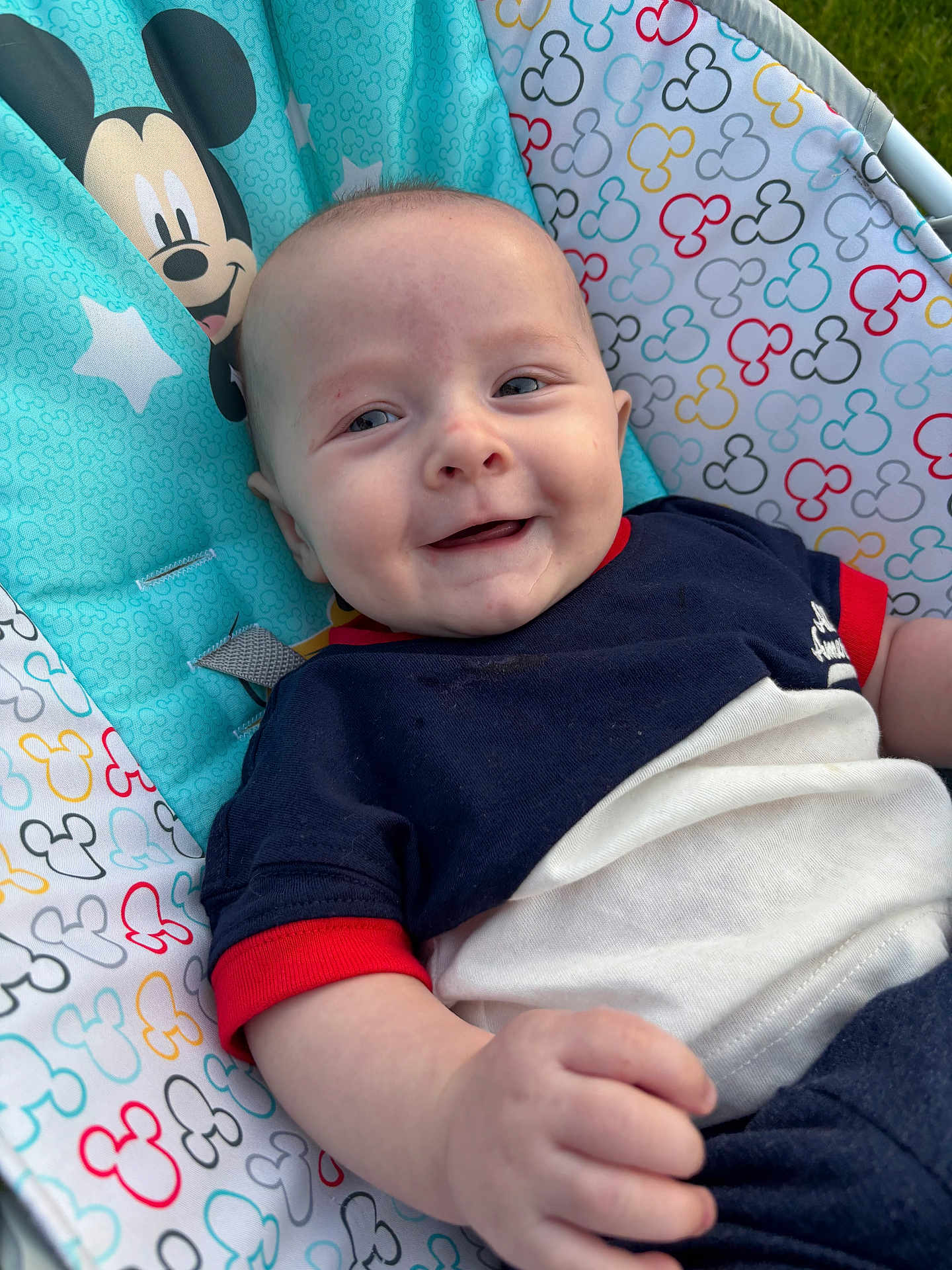Axel Scott is registered to the contest to win money with this photo: baby, smiling, infant, mickey_mouse, baby_seat, colorful, outdoor, clothing, happy, portrait, child, cute, seat, fabric, pattern, drool, person, young_child, relaxing, sunlight