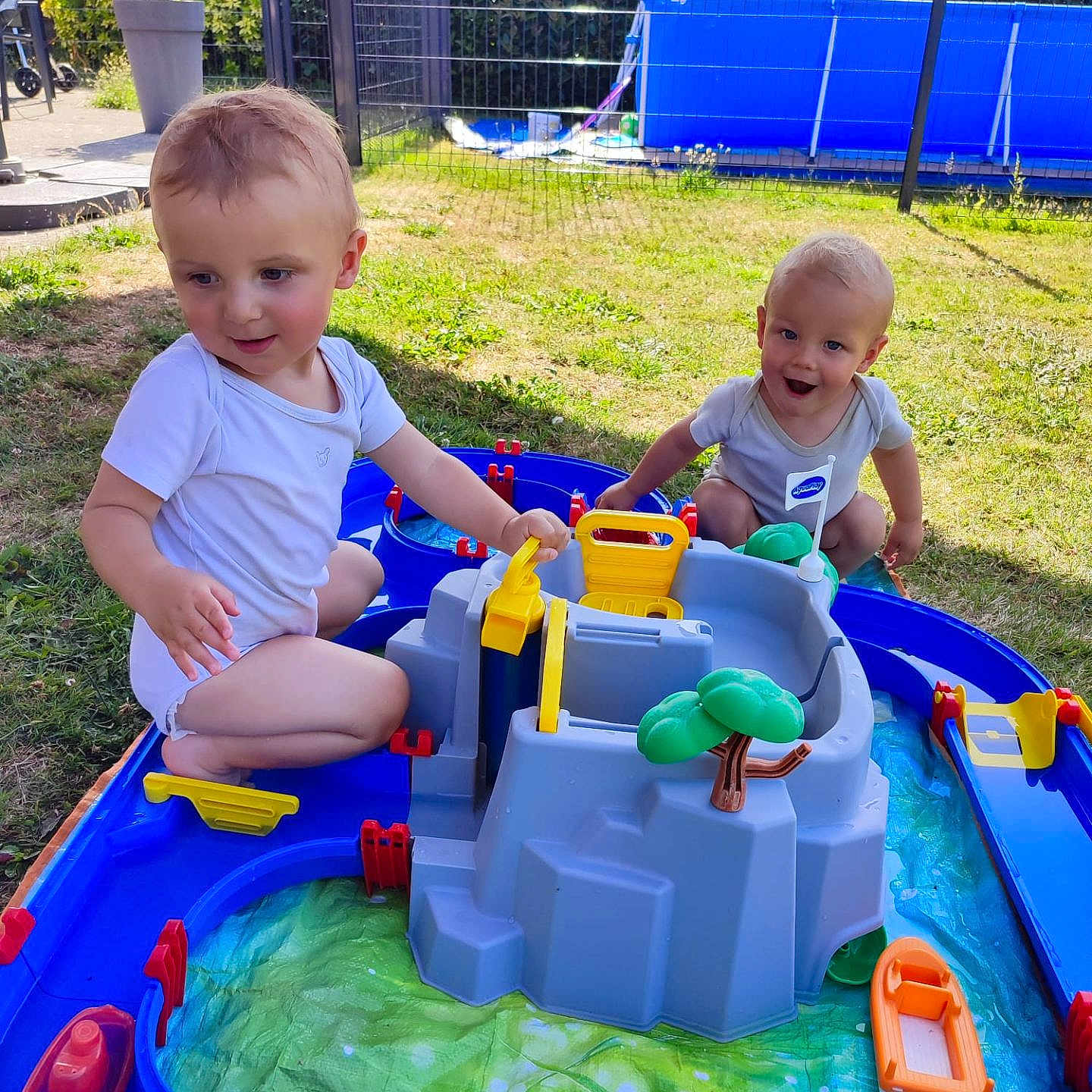 Juliann Kayronn a rejoint le concours — aidez-le/la à gagner de superbes lots ! blue, child, fence, garden, grass, green, happy, onesie, outdoor, plastic, play, short_hair, smile, summer, sunlight, toddler, toy, tree_toy, water_playset, yellow