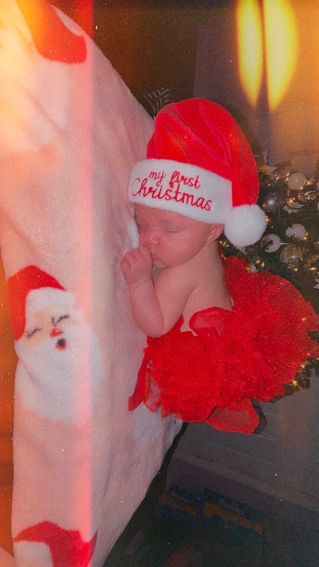 Zeanette is registered to the contest to win money with this photo: baby, infant, sleeping, christmas, holiday, santa_hat, red_tutu, blanket, santa_face, decorations, christmas_tree, lights, festive, cute, indoors, soft_lighting, holiday_season, newborn, peaceful, toddler
