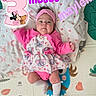 baby, infant, child, portrait, lying_down, pink_clothing, headband, dress, elephant_pattern, socks, play_mat, blanket, indoor, close_up, face, looking_at_camera, text_overlay, decorative_graphics, birthday_theme, photography