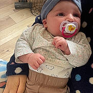 Elyne a rejoint le concours — aidez-le/la à gagner de superbes lots ! baby, pacifier, headband, floral_clothing, bear_pattern, polka_dot, hand, wooden_floor, table, bag, indoor, person, child, infant, resting, comfort, blanket, soft_toys, cute, warm