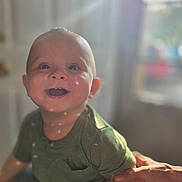 Liam joined the competition — help win amazing prizes! baby, child, smiling, happy, portrait, indoor, natural_light, lens_flare, green_shirt, person, infant, cute, hand, supporting_hand, face, eyes, skin, short_hair, toddler, warm