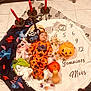 baby, costume, halloween, orange, plush_toys, pumpkin_bucket, candles, candy, blanket, numbers, floor_tiles, headwear, stuffed_animal, holiday, child, indoor, cute, festive, portrait, lying_down