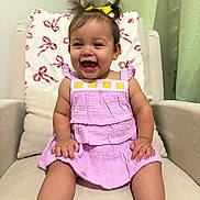 Amelia joined the competition — help win amazing prizes! baby, child, girl, smiling, happy, pigtails, yellow_bow, lavender_dress, sitting, armchair, cushion, indoor, cute, portrait, face, skin, footwear, bracelet, furniture, home