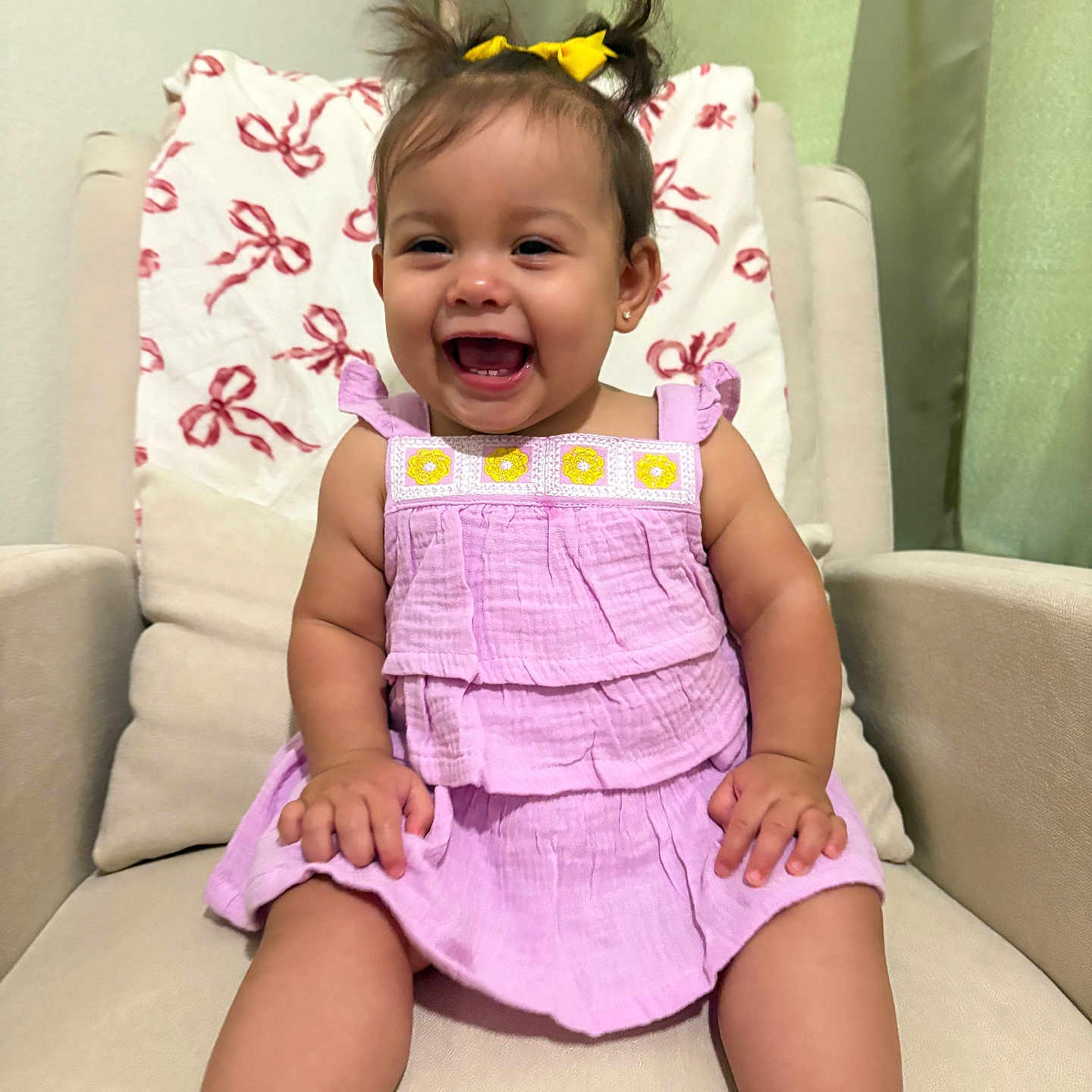 Amelia joined the competition — help win amazing prizes! baby, child, girl, smiling, happy, pigtails, yellow_bow, lavender_dress, sitting, armchair, cushion, indoor, cute, portrait, face, skin, footwear, bracelet, furniture, home