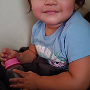 Katalina is registered to the contest to win money with this photo: blanket, blue_shirt, bottle, brown_hair, candid, child, closed_eyes, closeup, cozy, face, home, indoors, person, portrait, relaxed, sitting, sleepy, smiling, soft_lighting, toddler