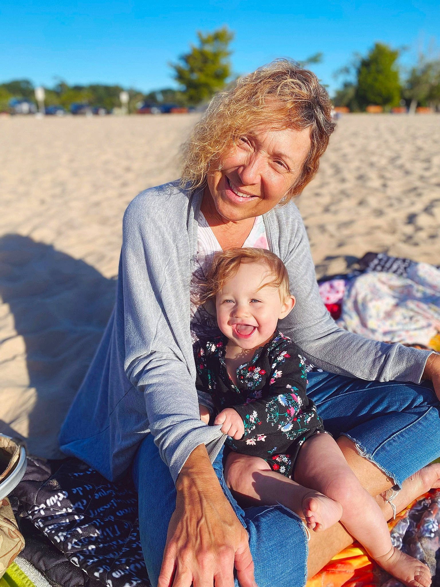 Liliana is registered to the contest to win money with this photo: azure, body_of_water, facial_expression, fun, grass, happy, human, joy, lap, leisure, mammal, people, people_in_nature, person, photograph, sky, smile, summer, sunlight, toddler
