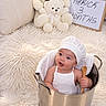 Herick is registered to the contest to win money with this photo: baby, infant, child, portrait, smiling, sitting, chef_hat, white_clothing, wooden_spoon, metal_bucket, teddy_bears, plush_toys, fluffy_rug, bedroom, pillows, milestone, three_months, celebration, indoor, cute