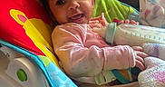 Sariyah joined the competition — help win amazing prizes! baby, baby_rocker, blanket, bottle, child, colorful, comfort, cozy, curly_hair, cute, feeding, happy, indoor, infant, milk, pink_clothing, seat, smiling, soft_lighting, toddler