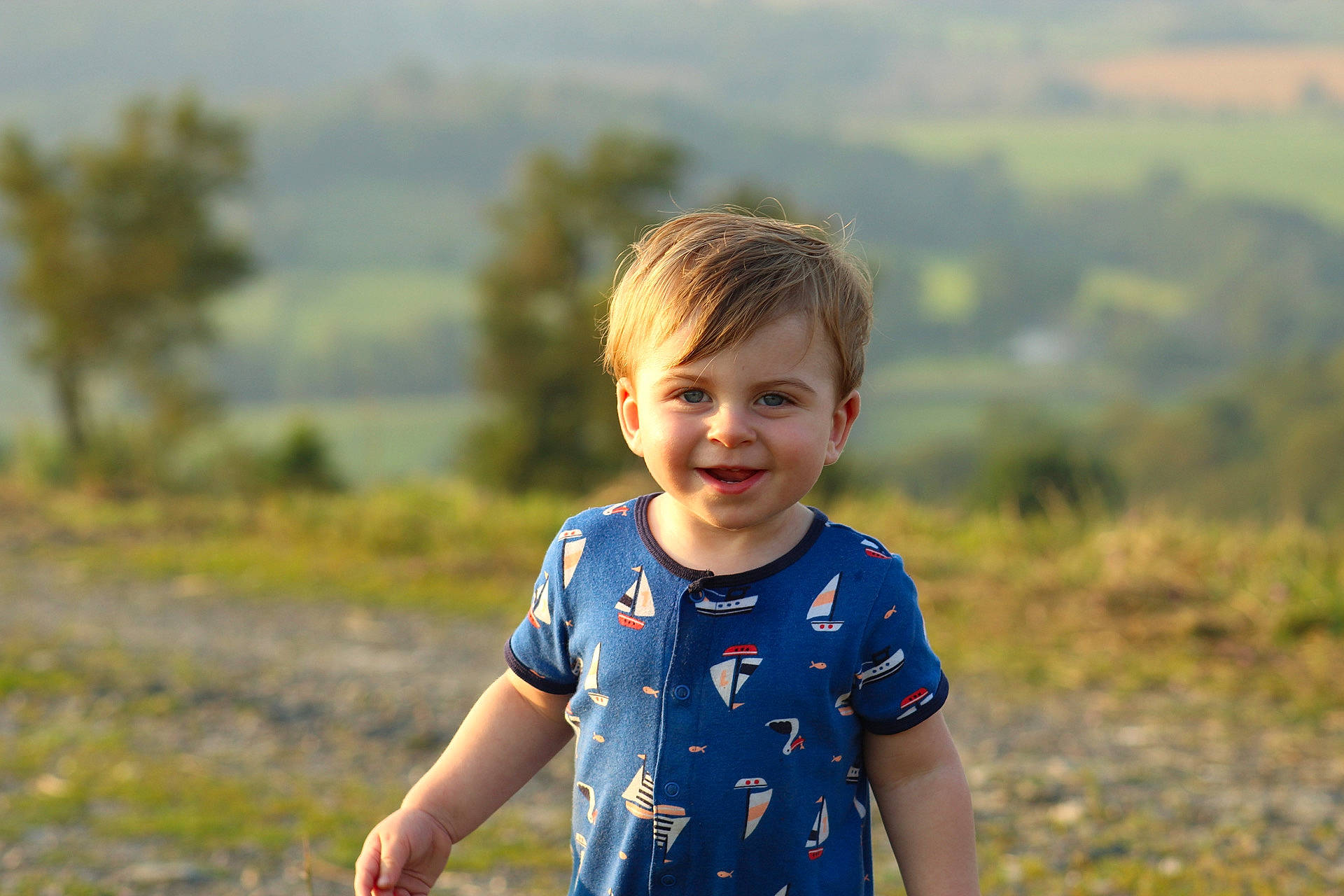 Chase is registered to the contest to win money with this photo: baby_toddler_clothing, electric_blue, fun, grass, grass_family, grassland, happy, joy, landscape, leisure, meadow, people_in_nature, person, plant, shoulder, sleeve, smile, summer, t_shirt, toddler