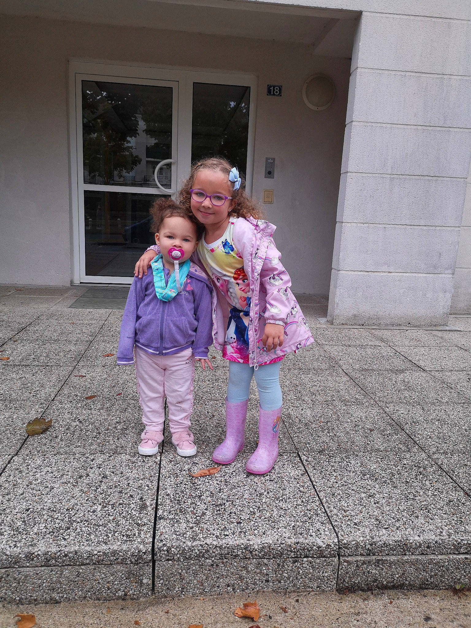 Liyanah participe au concours pour gagner de l'argent avec cette photo : asphalt, child, door, floor, flooring, fun, gesture, hair, head, human_body, human_settlement, interaction, joy, leisure, mammal, person, pink, road_surface, sidewalk, standing