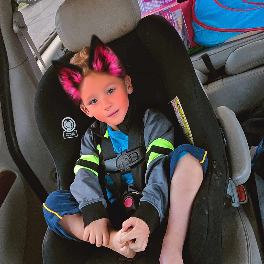 Hunter is registered to the contest to win money with this photo: barefoot, blue_clothing, car, car_interior, car_seat, casual, cat_ears, child, child_safety, cute, digital_filter, person, playful, seat, seatbelt, sitting, toy_box, vehicle, window, young