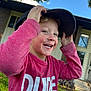 Hunter is registered to the contest to win money with this photo: child, boy, smiling, hat, red_shirt, outdoor, grass, bicycle, house, window, door, sky, cloud, tree, leaf, playful, happy, casual_clothing, daytime, portrait