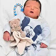 Tiago a rejoint le concours — aidez-le/la à gagner de superbes lots ! baby, newborn, sleeping, teddy_bear, blanket, mickey_mouse, clothing, infant, cute, soft_toy, bed, white, peaceful, child, portrait, indoors, small, hands, face, resting