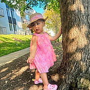 Elena Rose joined the competition — help win amazing prizes! apartment_building, child, curious, daylight, footwear, grass, hat, nature, outdoor, person, pink_crocs, pink_dress, playful, sidewalk, standing, straw_hat, sunny, toddler, tree, young_child