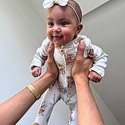 Elena Rose joined the competition — help win amazing prizes! baby, infant, child, hands, onesie, headband, smiling, cute, indoor, playful, person, human, holding, arm, wristwatch, happy, face, footed_pajamas, animal_print, portrait