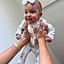 baby, infant, child, hands, onesie, headband, smiling, cute, indoor, playful, person, human, holding, arm, wristwatch, happy, face, footed_pajamas, animal_print, portrait