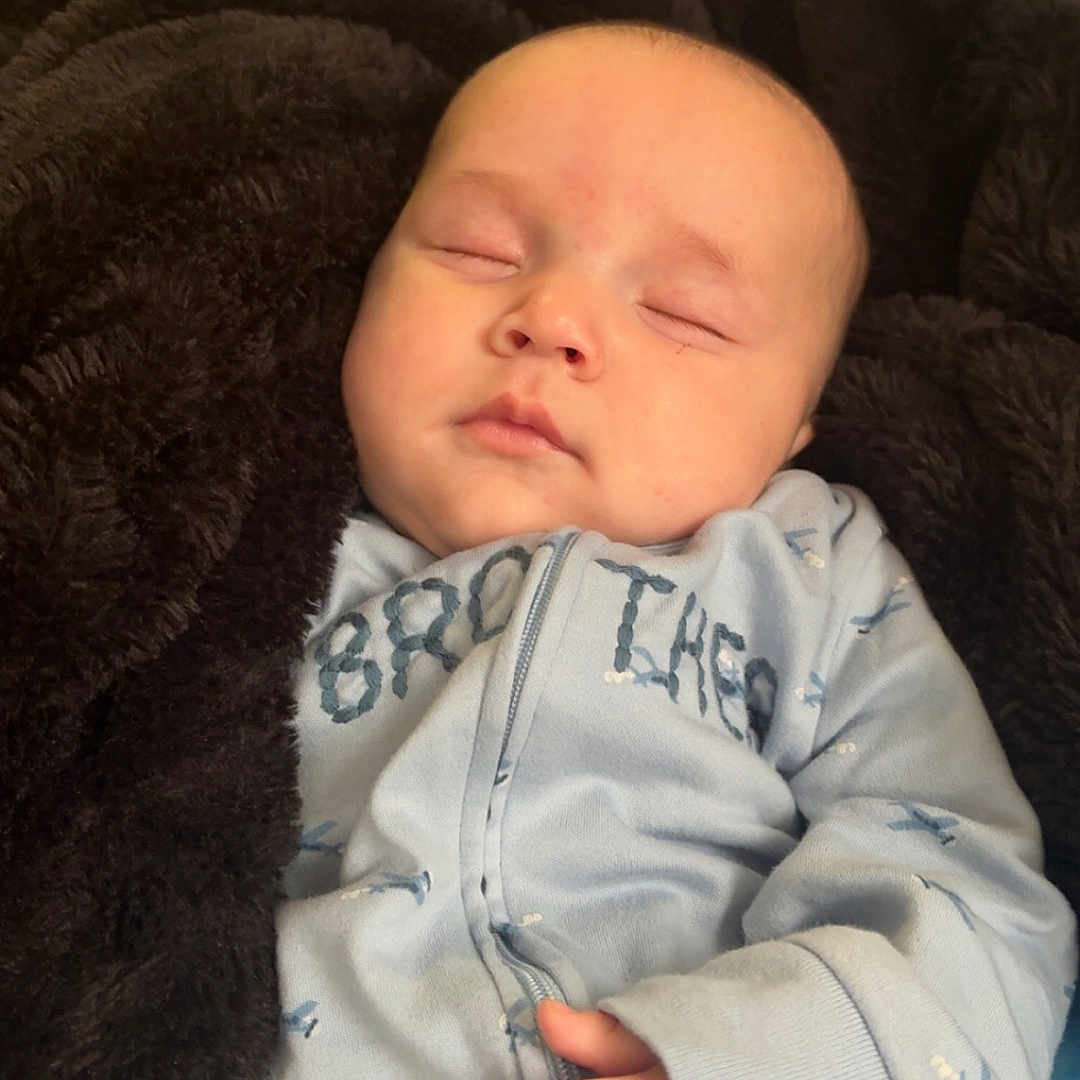 Bryson is registered to the contest to win money with this photo: baby, sleeping, blanket, blue_onesie, indoor, hand, face, infant, cozy, peaceful, clothing, child, soft, resting, newborn, portrait, cute, comfort, fan, bottle