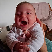 Emma a rejoint le concours — aidez-le/la à gagner de superbes lots ! baby, blanket, candid, chair, clothing, expression, face, family, furniture, hand, happy, holding, indoor, infant, person, portrait, skin, sleeve, smiling, young_child