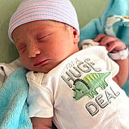 Deaklen is registered to the contest to win money with this photo: newborn, baby, sleeping, hat, onesie, dinosaur, blanket, infant, cute, child, soft, clothing, peaceful, resting, portrait, closeup, small, person, nursery, babywear