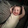 Connor is registered to the contest to win money with this photo: baby, smiling, infant, onesie, cushion, plush, texture, happy, relaxed, indoor, face, child, comfort, arm_raised, lying_down, cute, portrait, skin, head, young_child