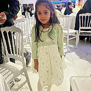 Cassie a rejoint le concours — aidez-le/la à gagner de superbes lots ! child, girl, dress, cardigan, white_chair, event, indoor, floor, people, table, lighting, smile, long_hair, white_shoes, tights, decor, portrait, standing, curious, fashion