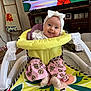 baby, bow, cartoon, child, colorful, cute, fisher_price, football_pattern, furniture, happy, headband, indoor, infant, living_room, person, pink_pants, smiling, socks, television, walker