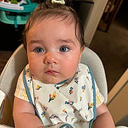 Violeta is registered to the contest to win money with this photo: baby, infant, child, high_chair, bib, floral, flowers, portrait, face, blue_eyes, brown_hair, sitting, indoor, home, baby_walker, furniture, photography, looking_at_camera, serious_expression, safe