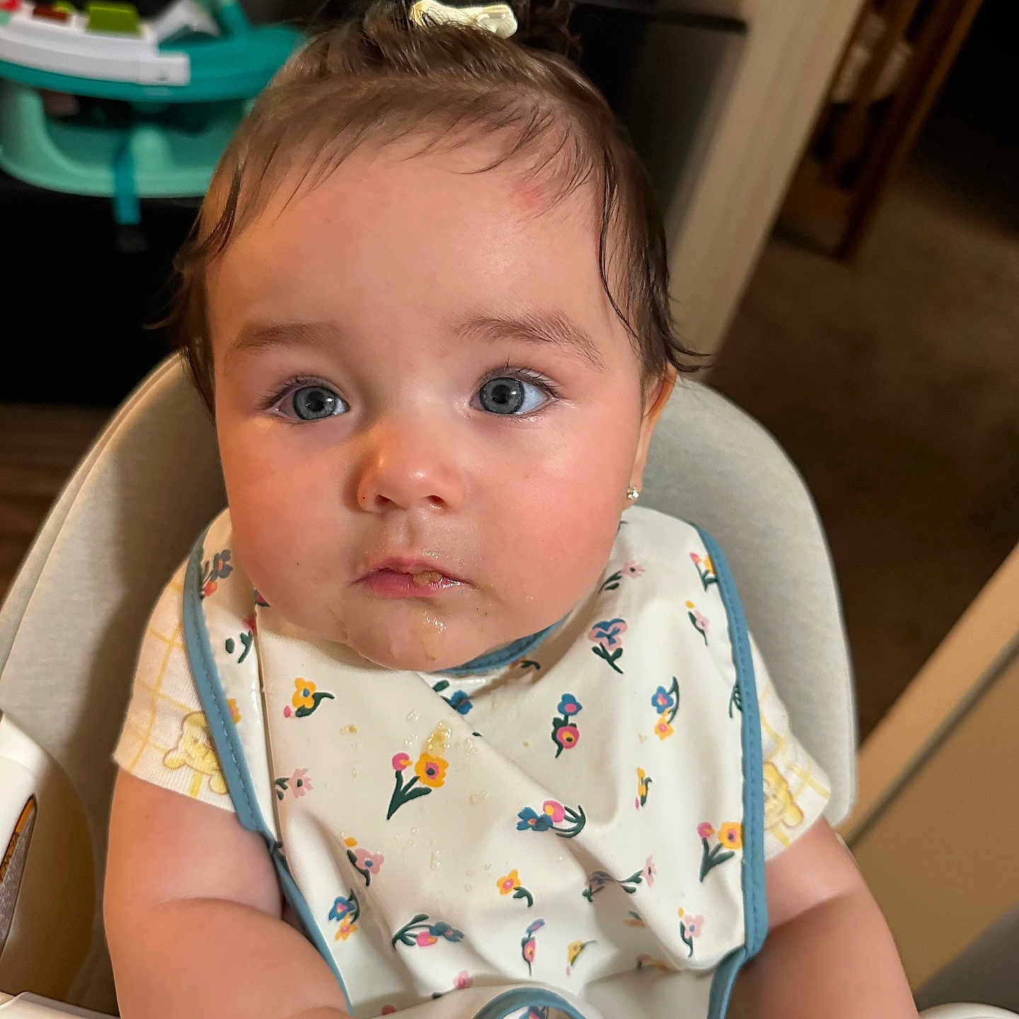 Violeta is registered to the contest to win money with this photo: baby, infant, child, high_chair, bib, floral, flowers, portrait, face, blue_eyes, brown_hair, sitting, indoor, home, baby_walker, furniture, photography, looking_at_camera, serious_expression, safe