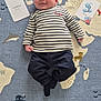 baby, infant, child, striped_shirt, pants, smiling, lying_down, milestone_cards, rug, world_map, animal_patterns, indoors, cute, portrait, young_child, playful, floor_mat, three_months, name_card, happy