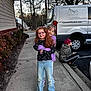 boy, building, child, children, curb, friends, girl, glasses, hugging, jacket, jeans, outdoor, parking_lot, red_hair, sidewalk, smile, sneakers, trees, van, vehicle