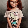 child, girl, pigtails, red_hair, glasses, hello_kitty, tshirt, smile, standing, portrait, casual_clothing, cute, young, happy, studio_background, hands_clasped, innocent, fashion, person, kid