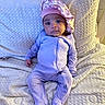 baby, infant, child, portrait, lying_down, blanket, bed, lavender, onesie, bonnet, floral, clothing, face, eyes, serious_expression, indoor, cozy, textile, photography, cute
