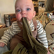 Sterling joined the competition — help win amazing prizes! baby, child, infant, face, blue_eyes, clothing, striped_shirt, overalls, blanket, hand, indoor, kitchen, person, seated, curious, rosy_cheeks, fabric, home, adult, cozy