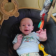 Felix is registered to the contest to win money with this photo: baby, baby_seat, child, clothing, colorful, cute, expression, fabric, face, hand, happy, indoor, infant, pattern, playtime, reaching, seat, smiling, toy, young_child
