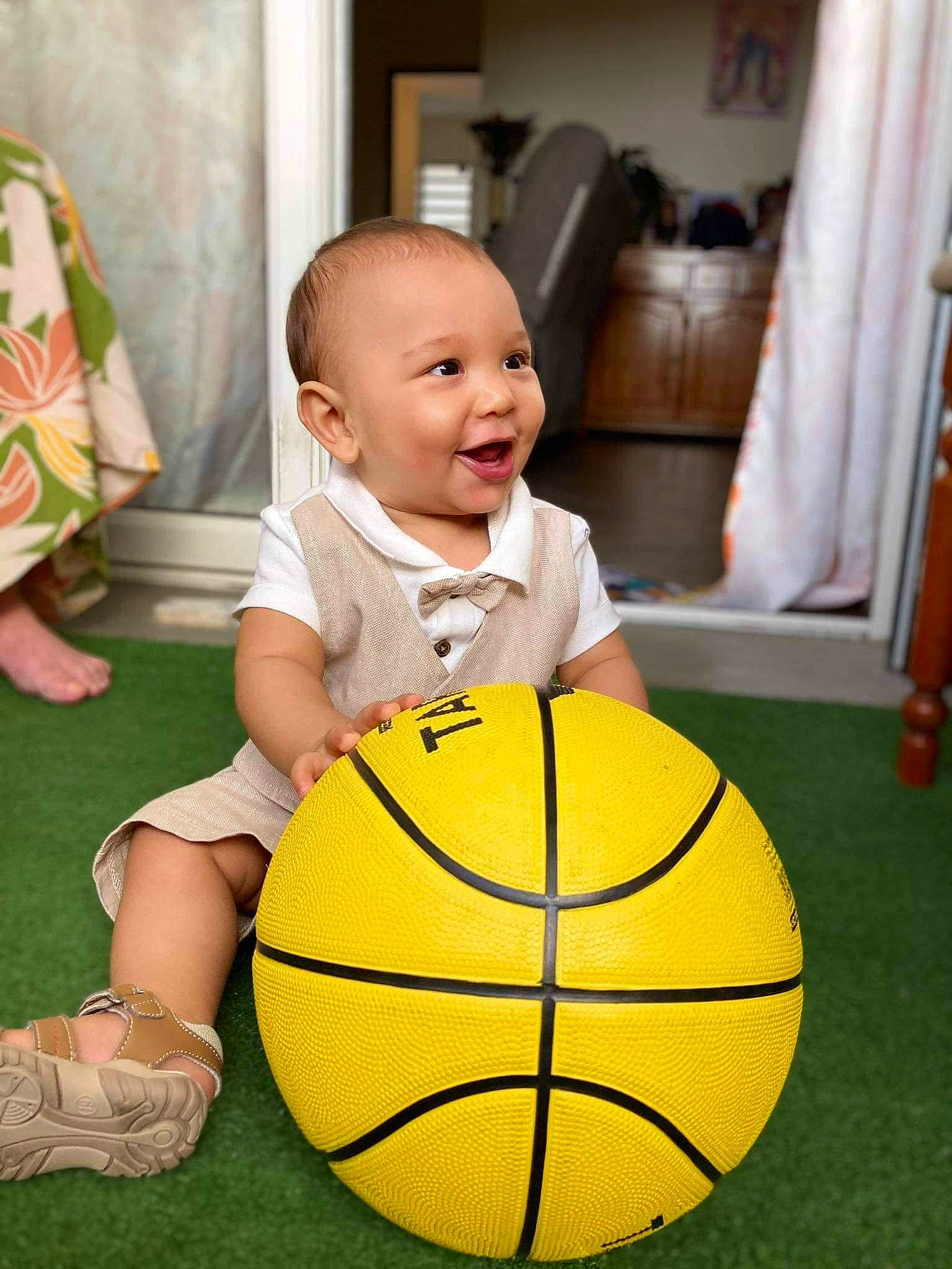 Liam a rejoint le concours — aidez-le/la à gagner de superbes lots ! baby_toddler_clothing, ball, basketball, child, curtain, eye, facial_expression, flooring, football, fun, grass, happy, person, photograph, picture_frame, shorts, smile, snapshot, sports_equipment, toddler