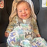 baby, smiling, blanket, car_seat, infant, face, child, happy, clothing, animal_print, cozy, seatbelt, indoors, cute, portrait, hood, person, young_child, comfort, warm