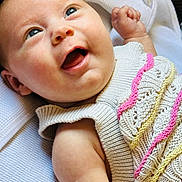 Ember is registered to the contest to win money with this photo: baby, blue_eyes, child, closeup, colorful, cute, face, happy, indoors, infant, knitted_clothing, lying_down, newborn, pink, portrait, skin, smiling, soft_texture, white, yellow