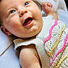 baby, blue_eyes, child, closeup, colorful, cute, face, happy, indoors, infant, knitted_clothing, lying_down, newborn, pink, portrait, skin, smiling, soft_texture, white, yellow